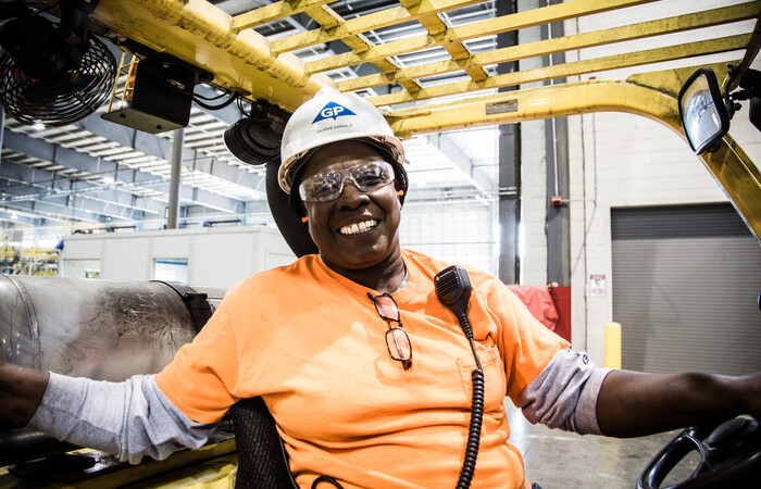 A female paper and wood products employee smiling brightly.