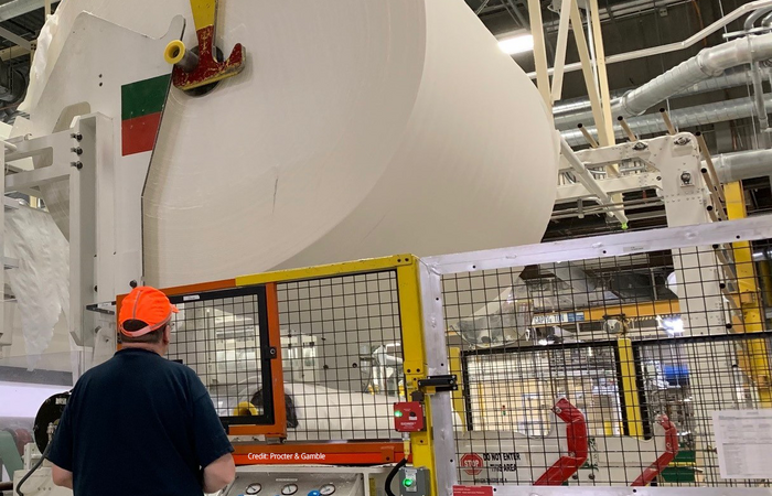 A man standing with a giant roll of tissue