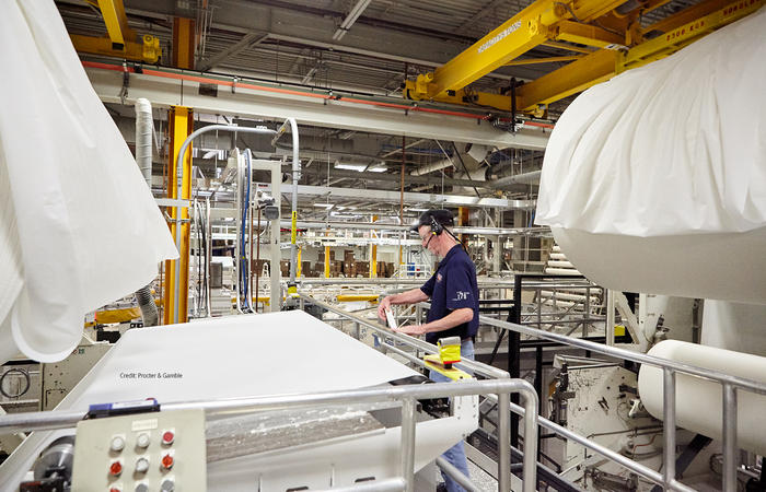 A man standing next to tissue being rolled out