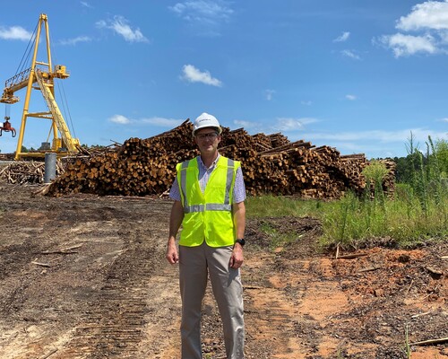 Tony Diaz stands in front of a log pile