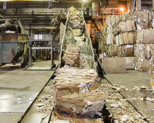 Bales of recycled cardboard going into a pulper at a paper mill.