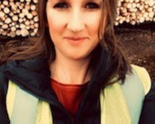 Denise Weinberger of Johnson Timber standing in front of a wood pile