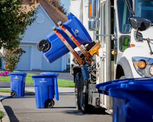 A recycling truck picking up recycling bins in a neighborhood