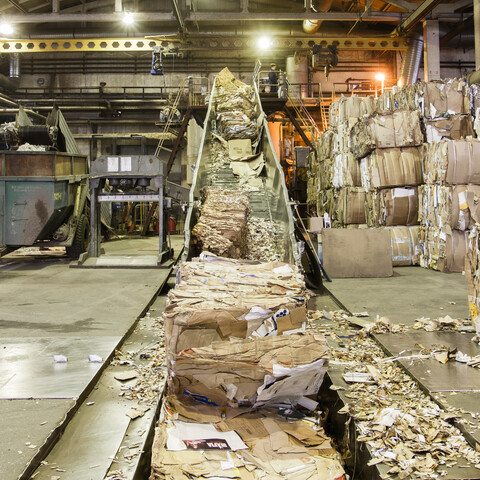 Bales of recycled cardboard going into a pulper at a paper mill.
