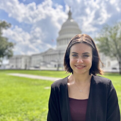 A photo of Sophie Bockman with the Capitol building in the background on a sunny but partly cloudy day.