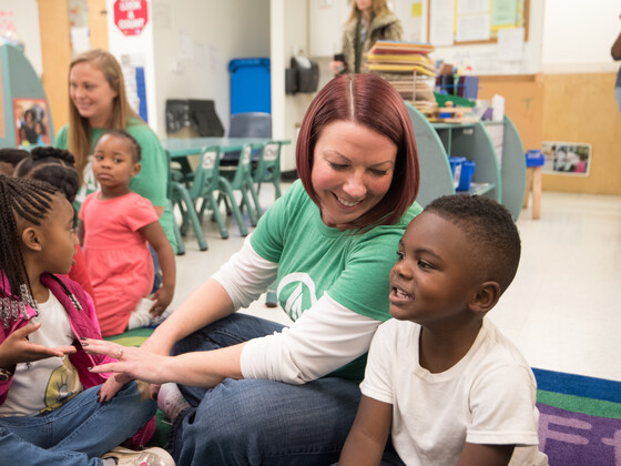 A woman sitting with a child at a school program.